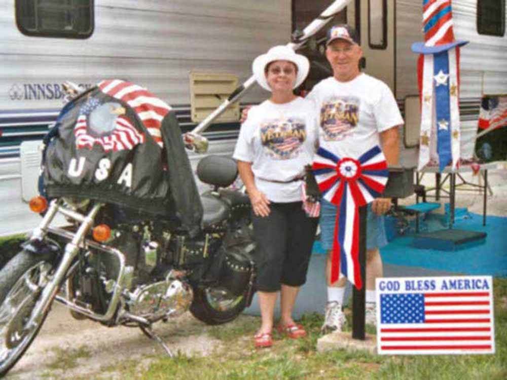 A couple standing next to a motorcycle at AMERICA'S BEST CAMPGROUND