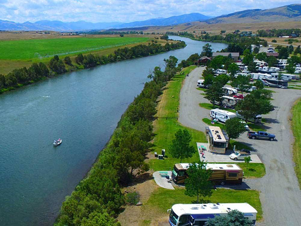 Aerial view of boat cruising down river alongside campground at YELLOWSTONE'S EDGE RV PARK