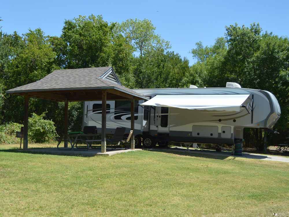 A fifth wheel trailer in a RV site with a covered patio at LOYD PARK CAMPING CABINS & LODGE