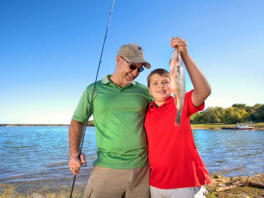 A father and son holding a fish at LOYD PARK CAMPING CABINS & LODGE