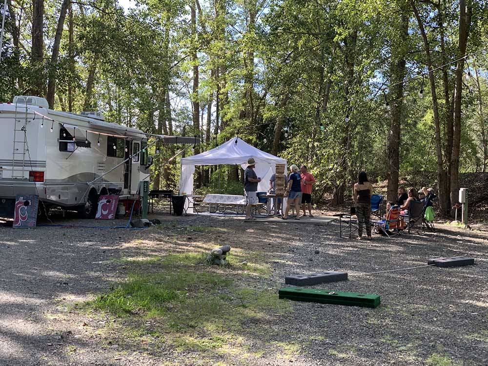 A group of people playing a game next to a motorhome at WHISPERING PINES RV CAMPGROUND