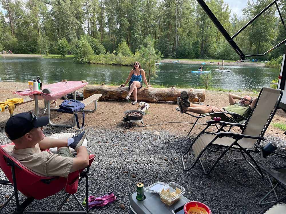 People in a campsite by the water at WHISPERING PINES RV CAMPGROUND