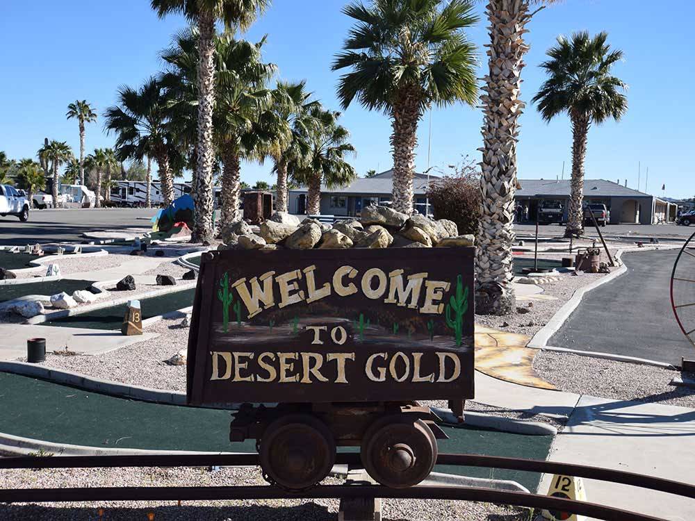 A Welcome sign next to the miniature golf at DESERT GOLD RV RESORT