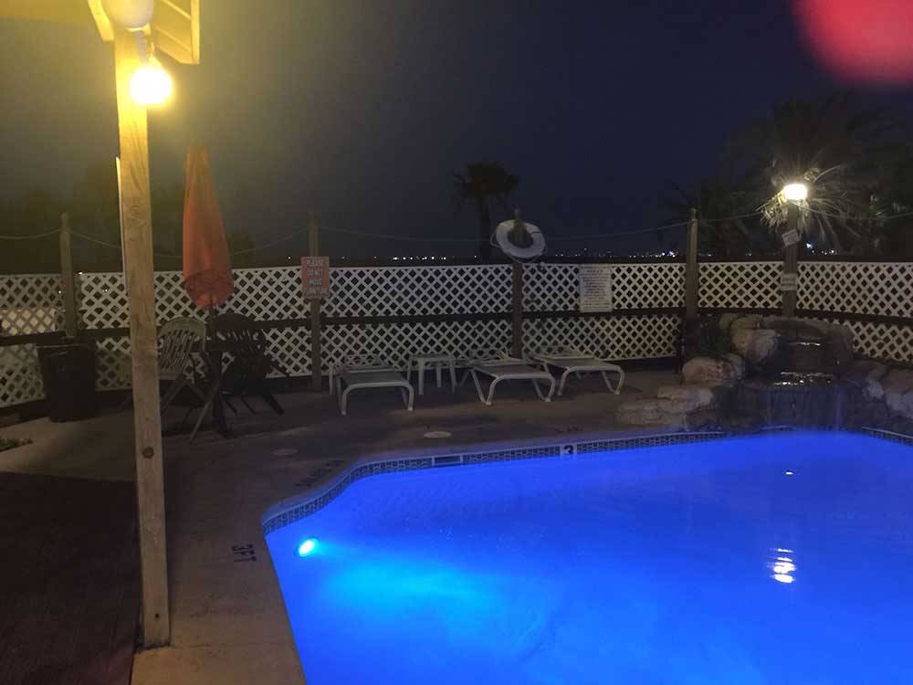 Lit public swimming pool with fountain in corner at night at SEA BREEZE RV COMMUNITY RESORT
