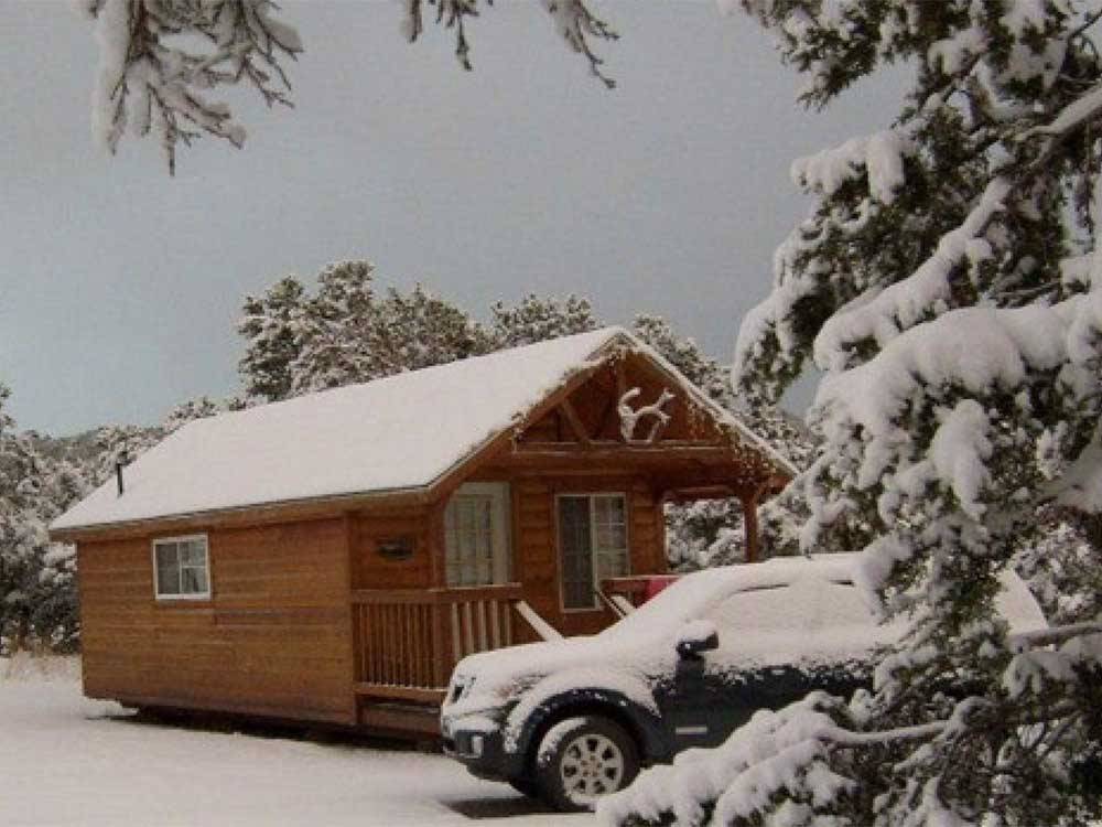 A cabin and SUV covered in a layer of snow at TURQUOISE TRAIL CAMPGROUND & RV PARK