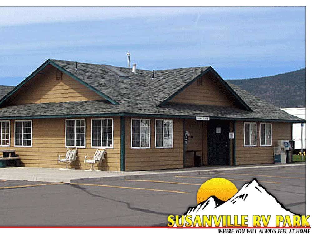 Outdoor seating for 2 in front of a brown and green building at SUSANVILLE RV PARK