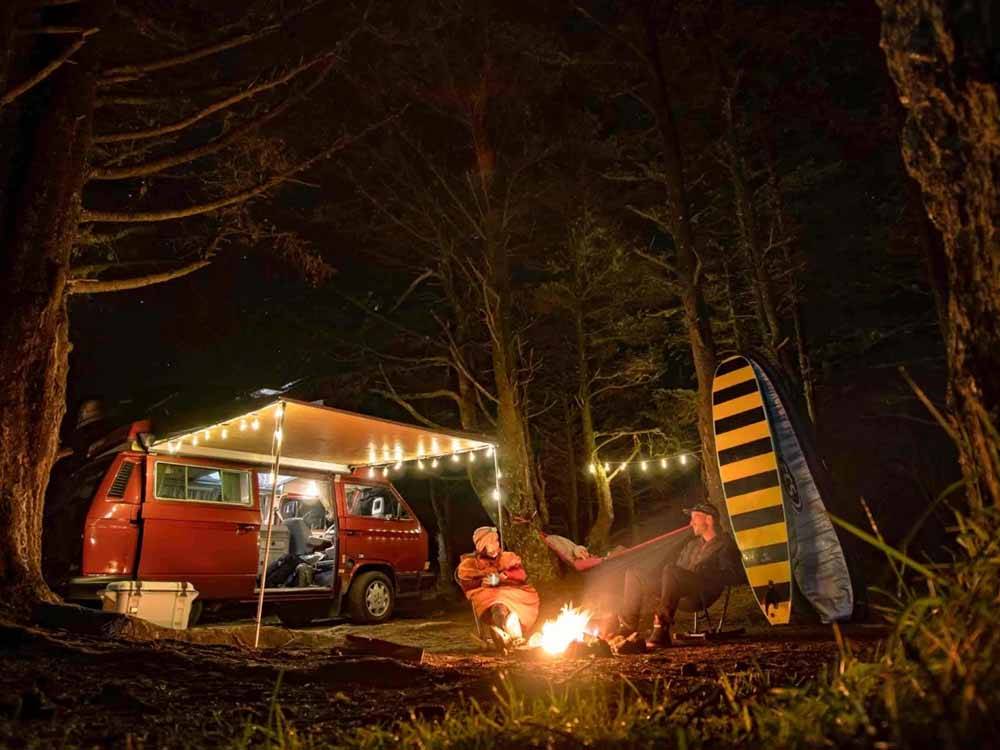 A couple sitting next to a fire at AMERICAN SUNSET RV & TENT RESORT