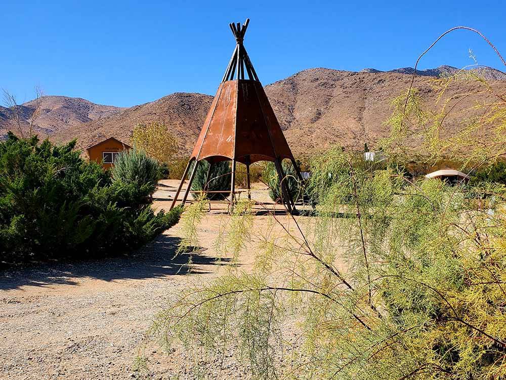 A metal teepee in the sand at STAGECOACH TRAILS RV PARK