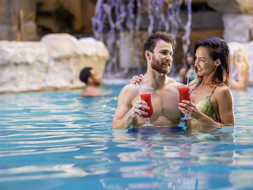 A couple enjoying a drink in the pool at PARAGON CASINO RV RESORT