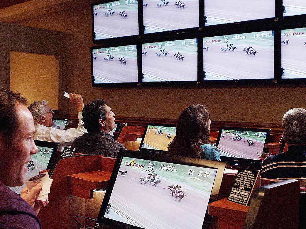 A group of people in the sports book watching horse racing at COUSHATTA LUXURY RV RESORT AT RED SHOES PARK