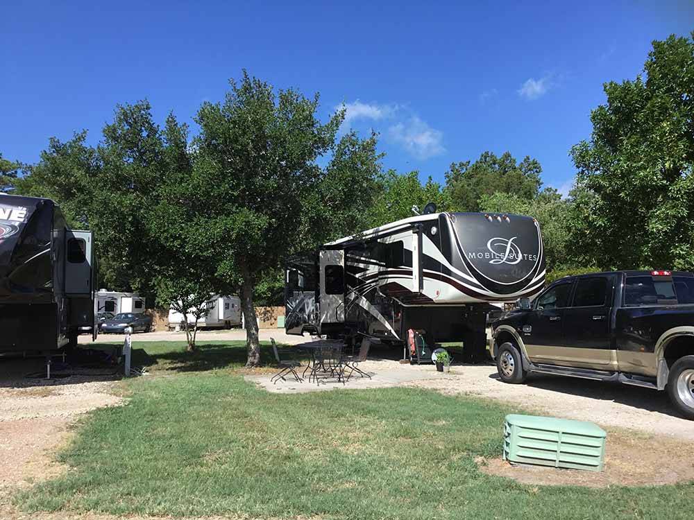 Fifth-wheel parked with truck in long sites near trees at WOODLAND LAKES RV PARK