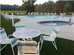 Swimming pool with lounge chairs and table at RALEIGH OAKS RV RESORT & COTTAGES - thumbnail