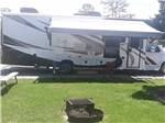 A trailer parked in a gravel site with a fire pit at RALEIGH OAKS RV RESORT & COTTAGES - thumbnail