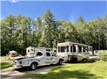 A white truck and trailer in a RV site at FIELD & STREAM RV PARK - thumbnail