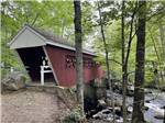 A red covered bridge over the stream at FIELD & STREAM RV PARK - thumbnail