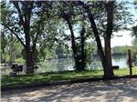 A picnic bench and BBQ by the water at CALDWELL CAMPGROUND & RV PARK - thumbnail
