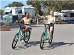 A couple of girls holding hands riding bikes at CAMPLAND ON THE BAY - thumbnail
