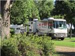 RVs and truck parked with yellow flowers in foreground at HOLIDAY RV PARK & CAMPGROUND - thumbnail