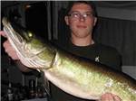A teenager holding a large fish at LAKE DUBAY SHORES CAMPGROUND - thumbnail