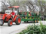 Man driving tractor giving families a ride in a wagon at CAMP A WAY RV PARK - thumbnail