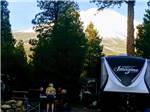 Campers relaxing and cooking next to fifth-wheel at FRIENDLY RV PARK - thumbnail