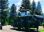 Fifth-wheel on paved site with mountain in background at FRIENDLY RV PARK - thumbnail
