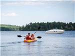 Man and woman kayaking on a lake near a boat at PATTEN POND CAMPING RESORT - thumbnail