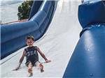 A boy sliding down an inflatable waterslide at CABOOSE LAKE CAMPGROUND - thumbnail