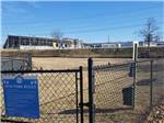 Black gate surrounding dog park with blue sign explaining the rules at CAMPING WORLD RACING RESORT - thumbnail