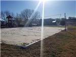 Sand volleyball court beside playground with sun at high noon at CAMPING WORLD RACING RESORT - thumbnail