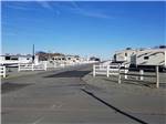 Roadway leading through RV park with trailers and white fencing on both sides at CAMPING WORLD RACING RESORT - thumbnail