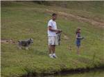 A dog watching people fish in the lake at SCENIC MOUNTAIN RV PARK & CAMPGROUND - thumbnail