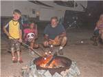 A family roasting marshmallows around a fire at SCENIC MOUNTAIN RV PARK & CAMPGROUND - thumbnail