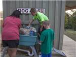 A family washing their dog in the dog wash area at SCENIC MOUNTAIN RV PARK & CAMPGROUND - thumbnail