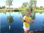 A kid holding a fishing pole with a fish at CAMP TURKEYVILLE RV RESORT - thumbnail