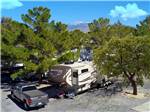 Trailer in a gravel site with pine trees at PREFERRED RV RESORT - thumbnail