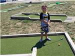 A small boy playing mini golf at THE RESORT AT ERIE LANDING - thumbnail