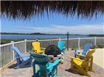 A group of colorful chairs around a fire pit overlooking the water at FISHERMAN'S COVE WATERFRONT RV RESORT - thumbnail