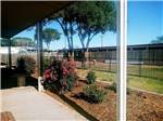 A porch overlooking a grassy area, plant bed and black fence at CLOVIS RV PARK - thumbnail