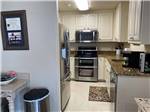 Kitchen area with stainless-steel microwave, oven and sink at CLOVIS RV PARK - thumbnail