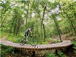 A man on a bike on a wooden bridge at BLOWING SPRINGS RV PARK - thumbnail