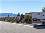 RV sites line a paved road with mountains in background at SUN RESORTS RV PARK - thumbnail
