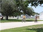 Two people riding their bikes on one of the roads at VICTORIA COLETO LAKE RV RESORT - thumbnail