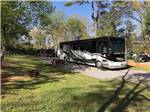 A black and white motorhome parked in a gravel site at KOUNTRY AIR RV PARK - thumbnail