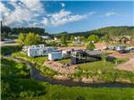 Motorhomes and trailers backed in by the water at BLACK HILLS TRAILSIDE PARK RESORT - thumbnail