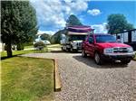 A car and motorhome in a gravel RV site at GREEN ACRES RV PARK - thumbnail