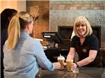 A woman handing another woman a couple of coffees at THE RV PARK AT ROLLING HILLS CASINO AND RESORT - thumbnail