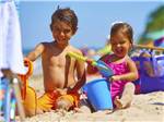 Young boy and girl in pink bathing suit playing on the beach at CAPE CHARLES/CHESAPEAKE BAY KOA RESORT - thumbnail