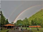 Double rainbow in background of wooden cabin and playground at PIGEON RIVER CAMPGROUND - thumbnail