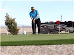 A man playing golf next to a motorhome at ROUTE 66 RV RESORT - thumbnail